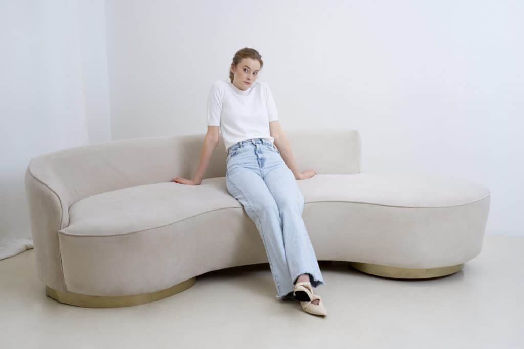 A woman sitting on a large and awkwardly shaped sofa